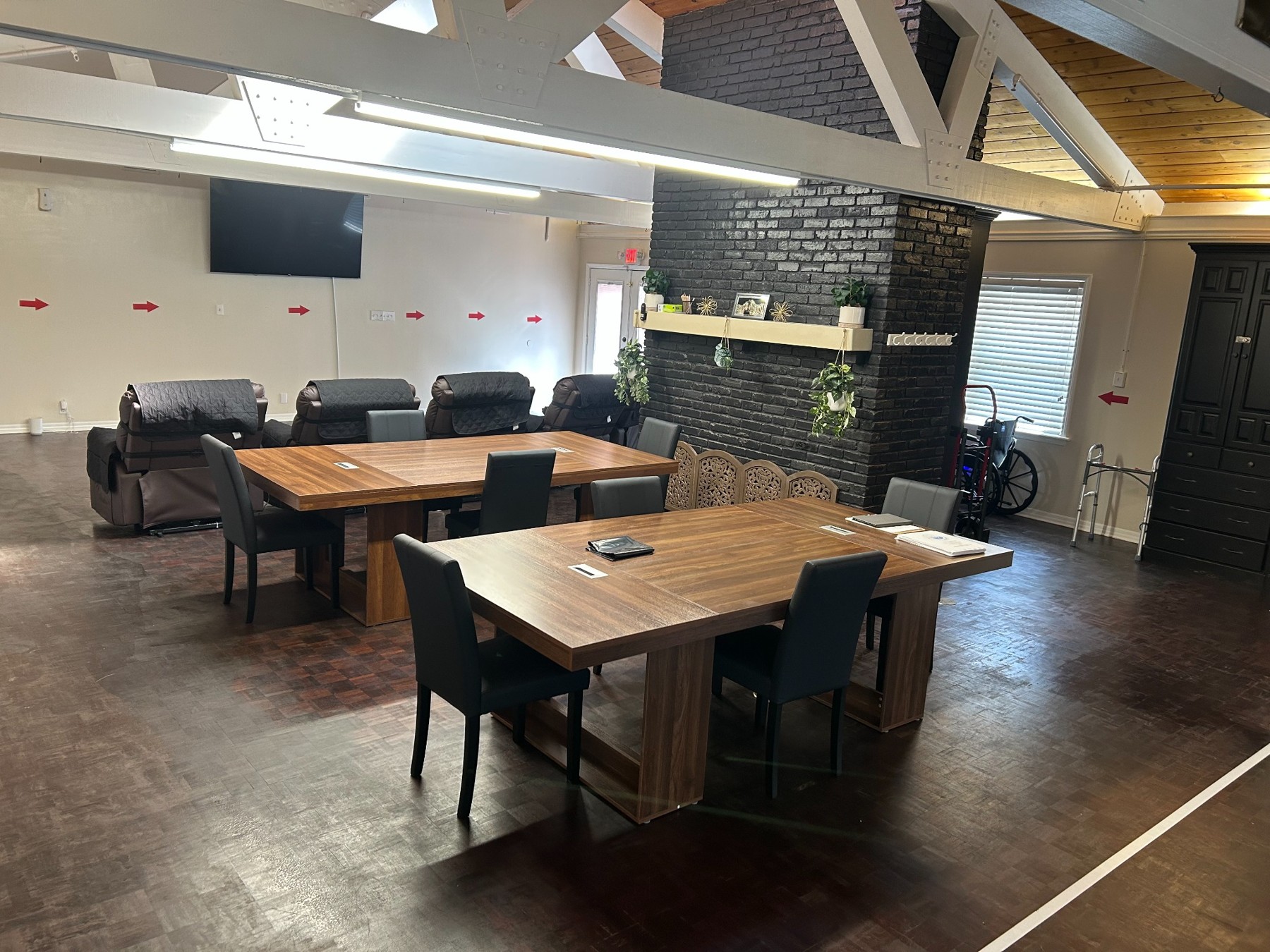 Dining tables, chairs, and living area beside a brick fireplace