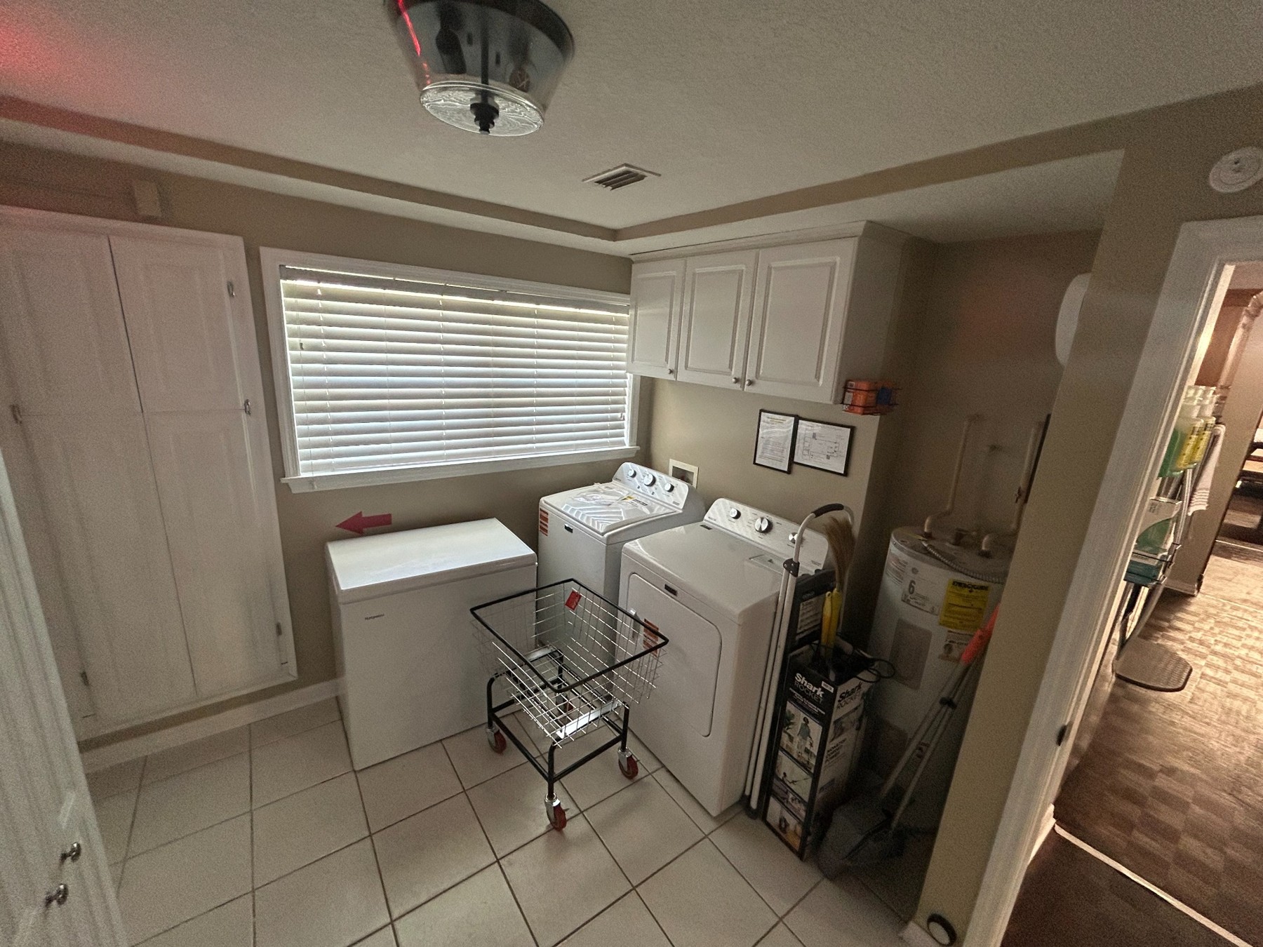 Laundry room with washer, dryer, cabinets, and a window
